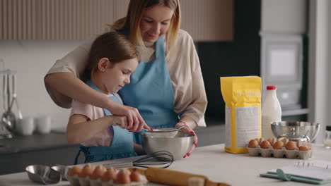 Madre-E-Hija-Están-Cocinando-Pastel-En-La-Cocina-De-Casa-Tamizando-Harina-Para-Masa,-Pasatiempo-Conjunto-Y-Educación-Para-Niños-Pequeños